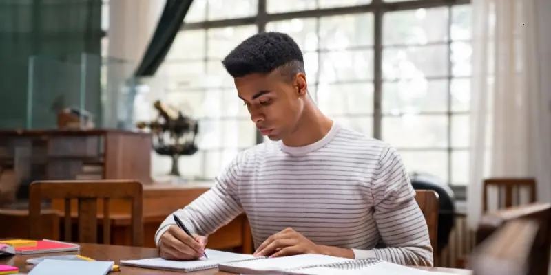 Student Mental Toughness Focus Study Student writing in a notebook, focused on studying.